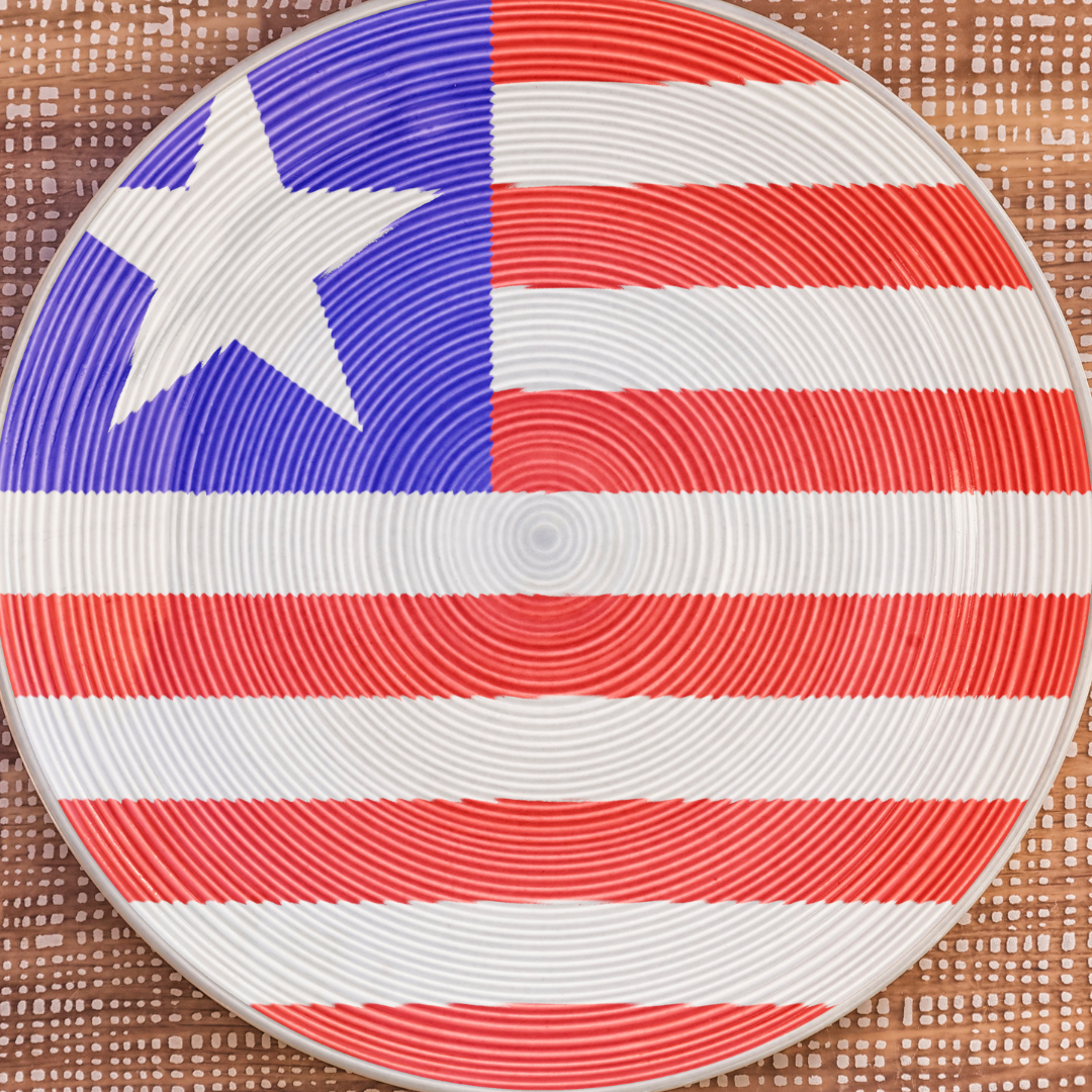 a dinner plate on a woven brown placement with the liberian flag painted on it